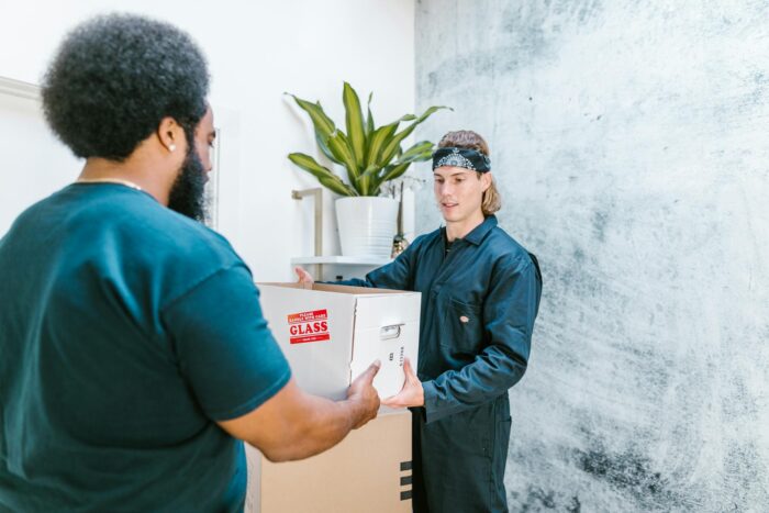 Close-up of delivery professionals exchanging packages indoors, showcasing efficient service.