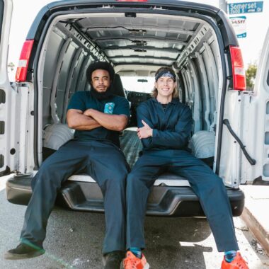 Two movers sitting in the back of a van, arms folded, ready for work.